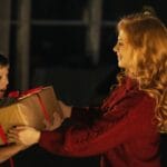 Jak podarować motywację? Prezenty fitness, które wspierają nawyki Mama wręcza synowi świąteczny prezent w domu