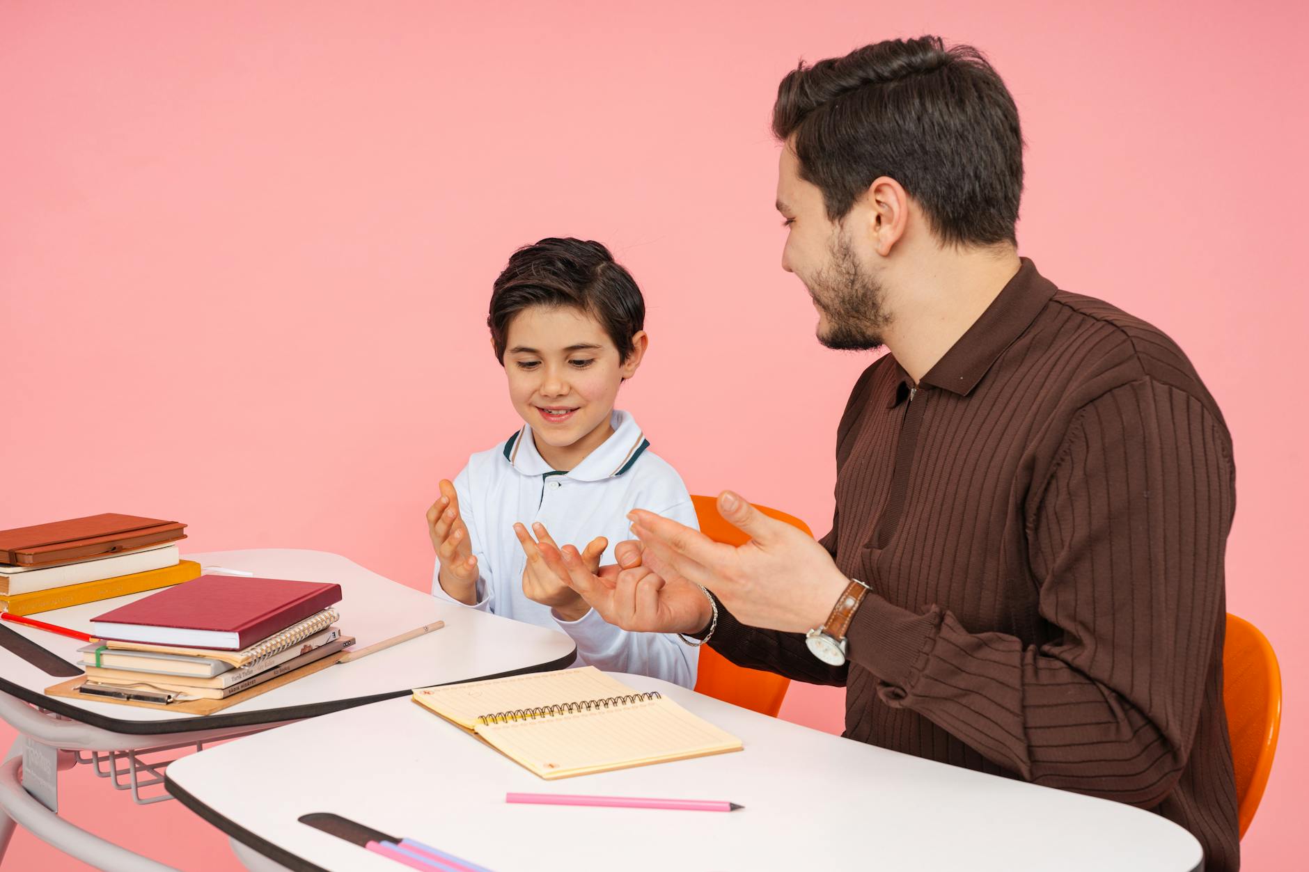 Nauczyciel i uczeń rozmawiają przy biurku w sali lekcyjnej