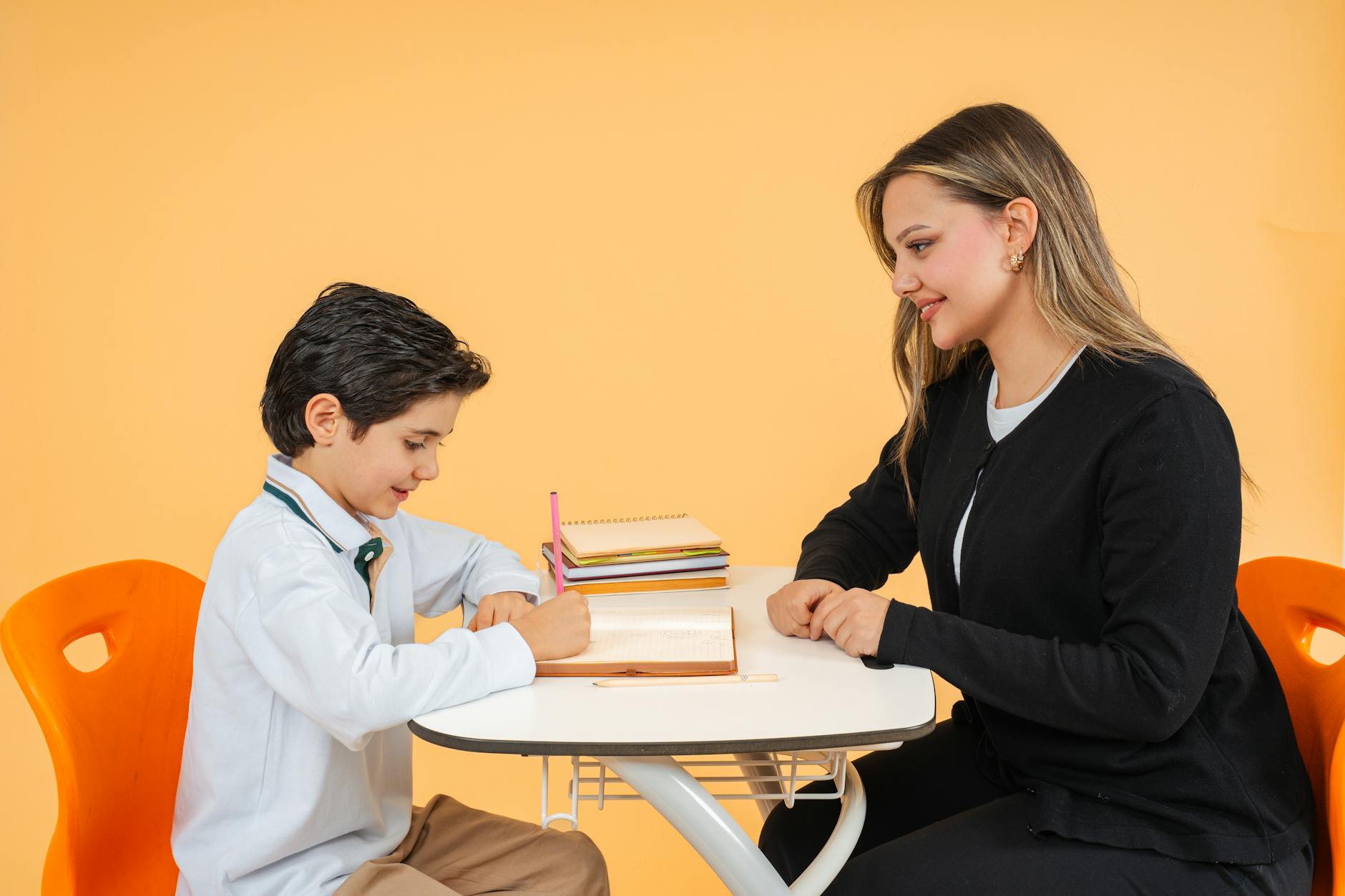 Nauczycielka pomaga uczennicy w odrabianiu zadania przy szkolnej ławce