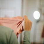 Dziewczynka przymierza różową sukienkę przed lustrem w jasnym pokoju
