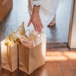 Prezent na ostatnią chwilę dla niej do 300 zł: eleganckie pewniaki Kobieta odbiera torby z prezentami zamówionymi online przy drzwiach