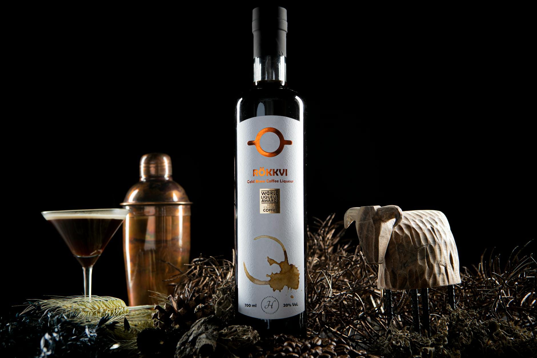 Domowy likier kawowy DIY w butelce premium: przepis i etykieta Butelka domowego likieru kawowego z kieliszkiem na ciemnym tle