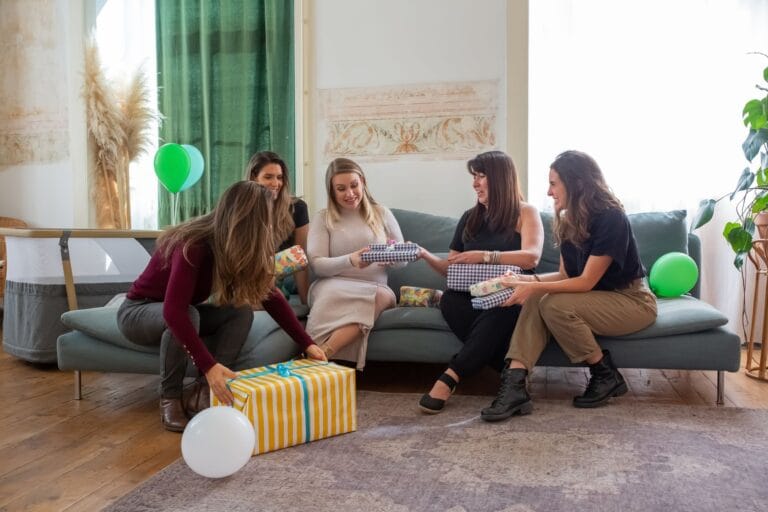 Kobiety świętujące baby shower i wręczające prezenty w domu